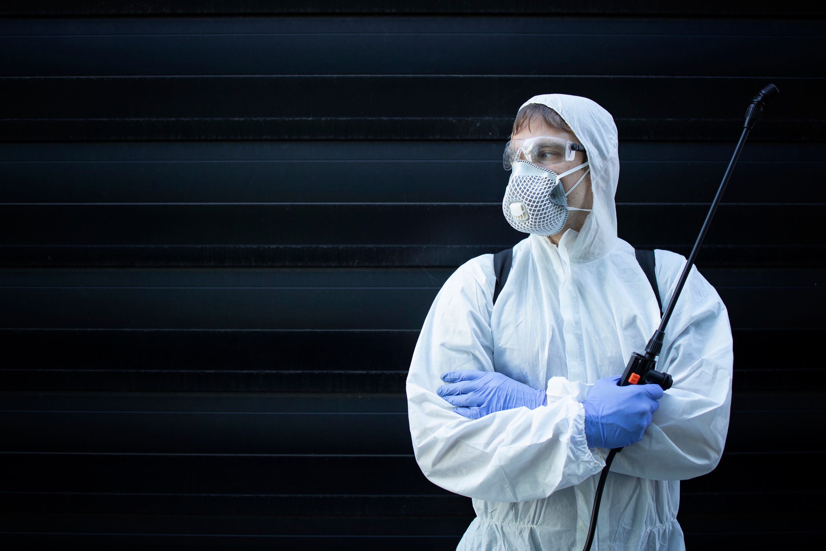 Portrait of professional exterminator holding sprayer with chemicals for pest control. Copy space provided.